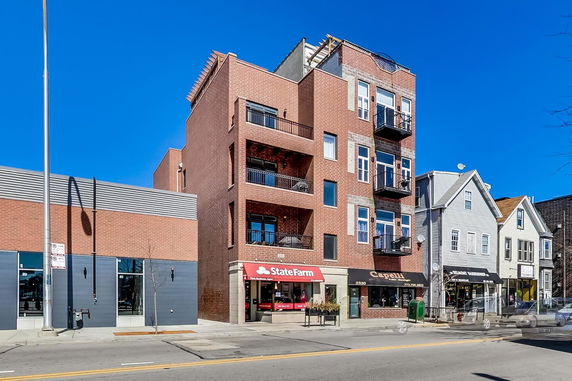 Front view of a multi-story building with commercial units on the ground floor.