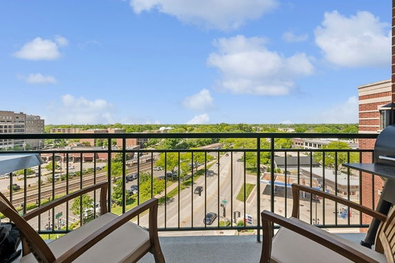 Panoramic view from a balcony overlooking streets, buildings, and greenery.