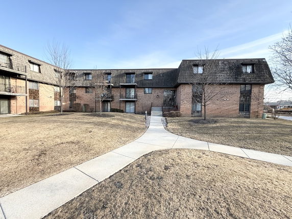 Front view of a multi-story brick apartment building with a mansard roof.