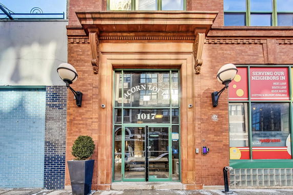 Front view of a brick commercial building with large glass entrance with Acorn Loft signage.