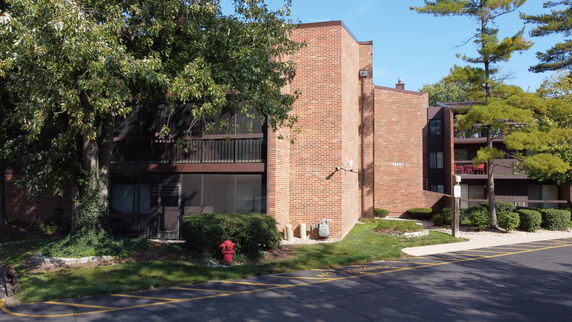 Front view of a multi-story brick apartment building with balconies.