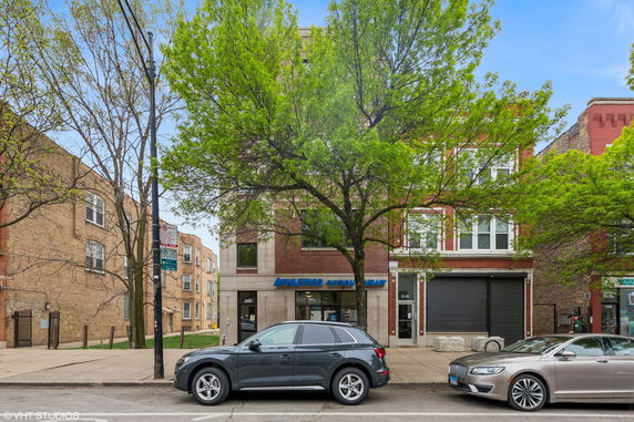 Front view of a multi-story brick building with commercial space on the ground floor.