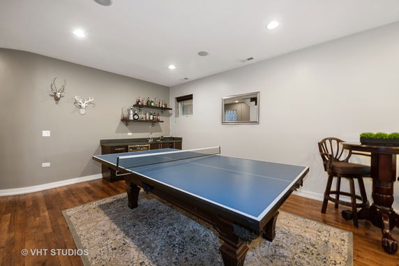 Indoor area with a ping pong table, bar counter, and wall-mounted shelves.