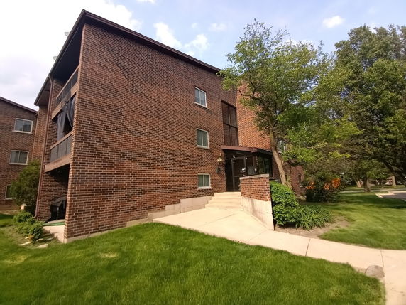 Front view of a multi-story brick building with balconies and a glass entrance.