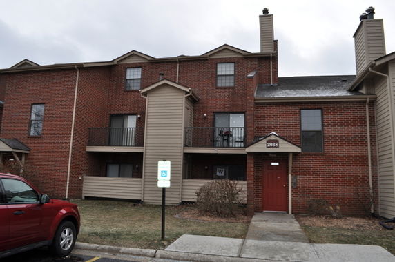 Front view of a three-story building with brick facade and balconies.