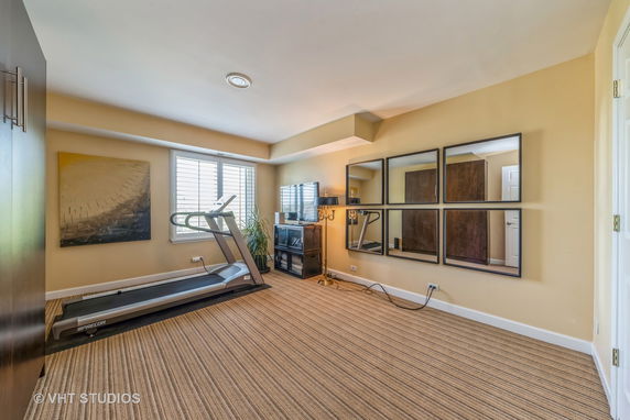 Room with a treadmill and wall mirrors.