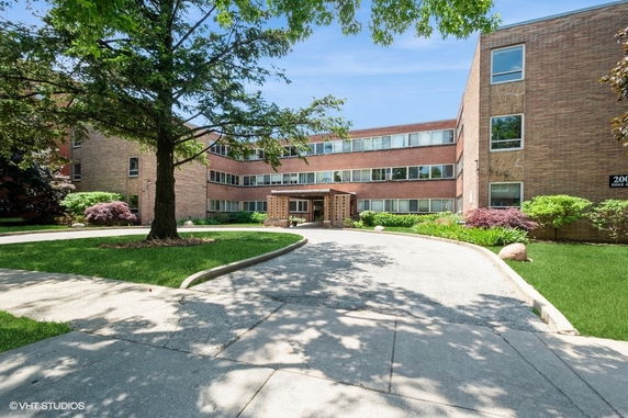 Front view of a multi-story brick apartment building with a driveway.
