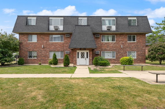 Front view of a three-story brick apartment building with multiple windows and a central entrance.