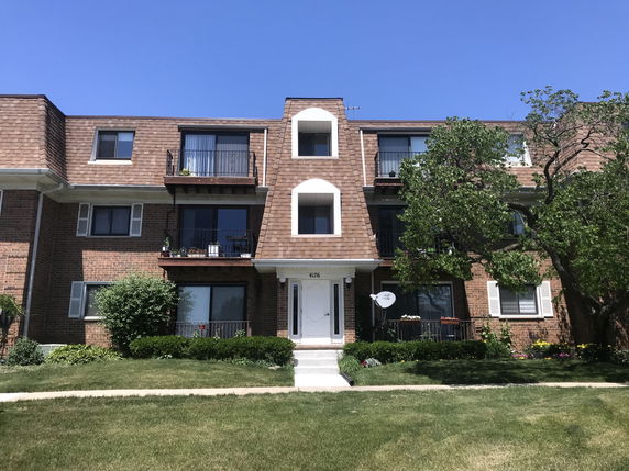 Front view of a three-story brick apartment building with balconies.