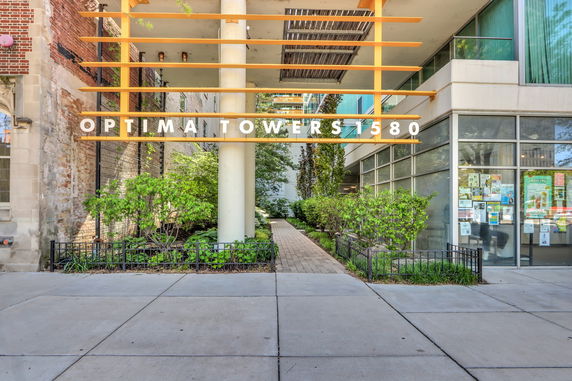 Front view of a building with 'OPTIMA TOWERS 1580' sign and entrance walkway.