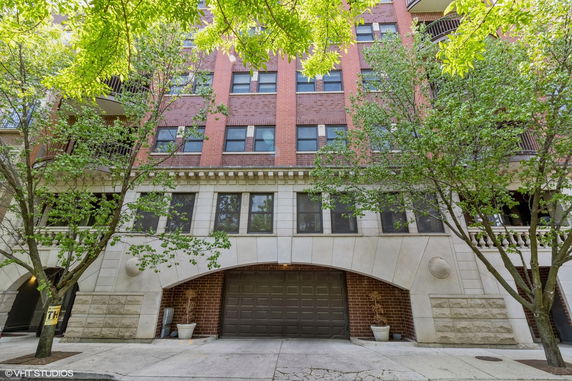 Front view of a multi-story residential building with a brick facade and garage entrance.