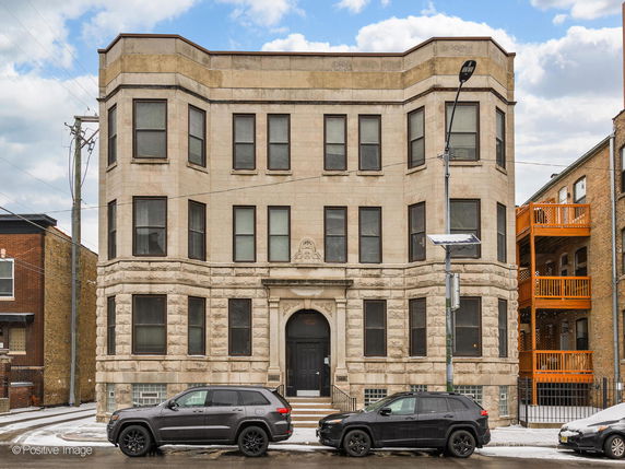 Front view of a three-story building with a symmetrical design and multiple windows.