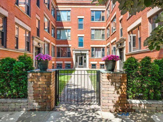 Front view of a multi-story brick building with a gated entrance.
