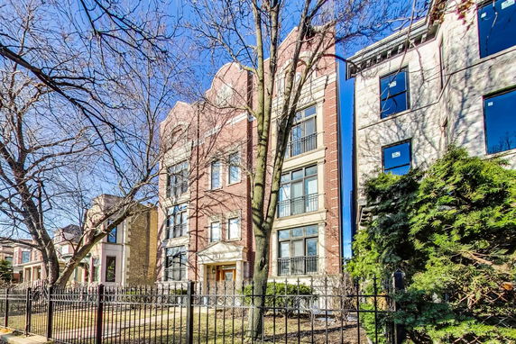 Front view of a multi-story brick building with large windows and iron fencing.