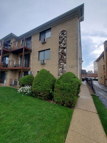 Front view of a multi-story building with balconies and a brick facade.