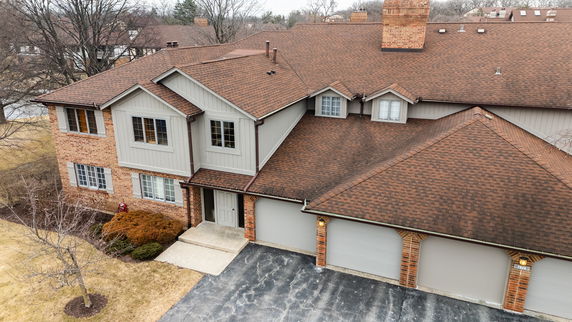Front view of a multi-story house with brown shingle roof and attached garages.