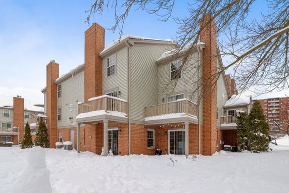 Front view of a multi-story building with brick exterior and balconies covered in snow.