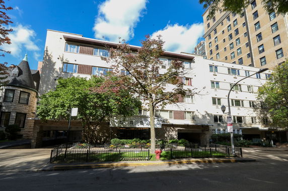 Front view of a multi-story residential building with a landscaped entrance.