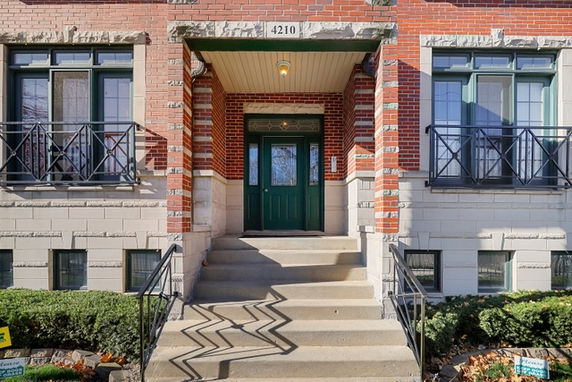 Front view of a multi-story building with a central entrance and brick facade.