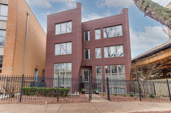 Front view of a modern three-story brick building with large windows and a central entrance.