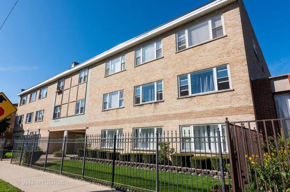 Front view of a three-story brick apartment building with multiple windows.