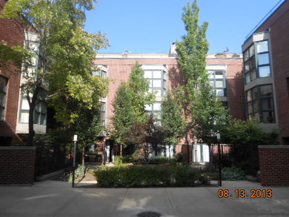 Front view of a multi-story brick building with large windows and surrounding trees.