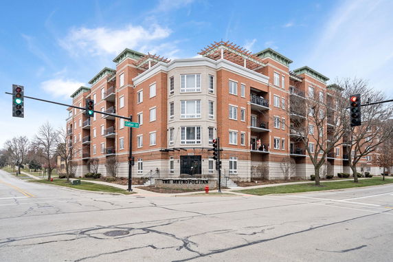Front view of a multi-story brick apartment building at an intersection.