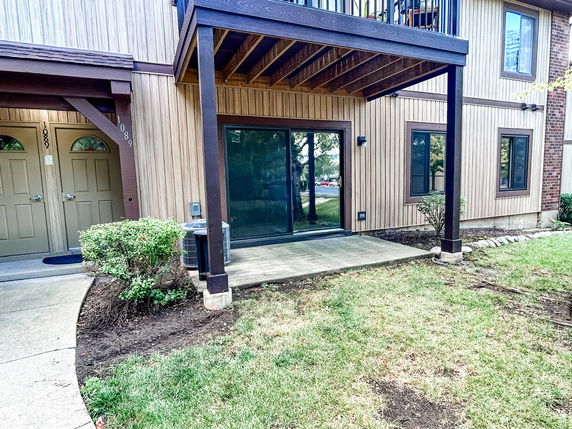 Front view of a two-story building with wooden siding and a covered patio.