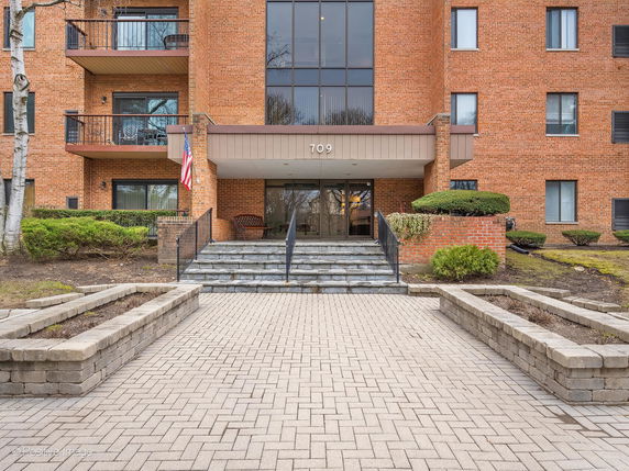 Front view of a brick apartment building with balconies and entrance steps.