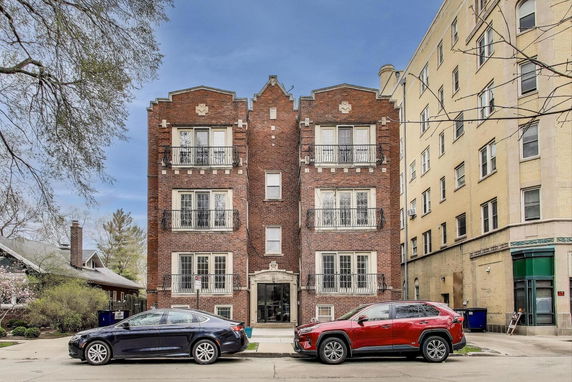 Front view of a four-story brick apartment building with balconies.