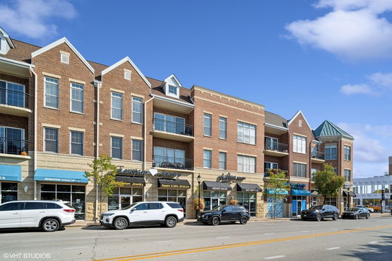 Front view of a multi-story brick building with balconies and commercial spaces on the ground floor.