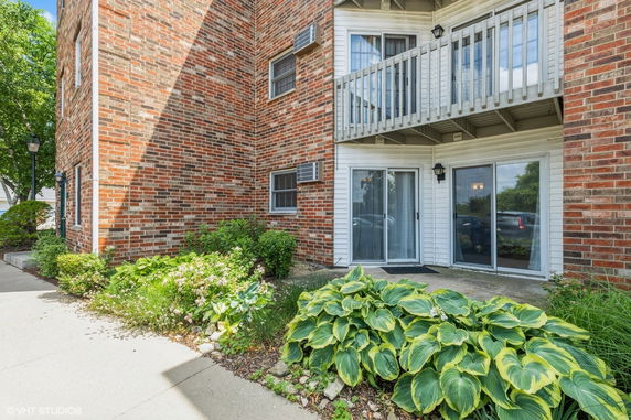 Front view of a brick building with a small balcony and sliding glass doors.