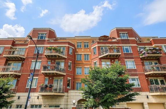 Front view of a multi-story apartment building with balconies and red brick exterior.