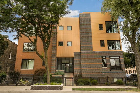 Front view of a modern multi-story building with brick and wood paneling.