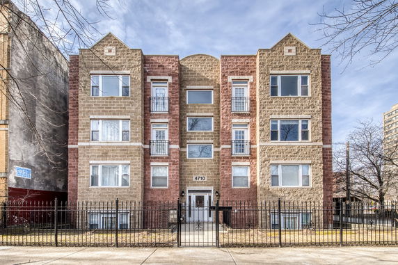 Front view of a multi-story apartment building with a gated entrance.