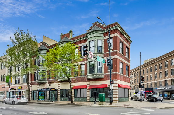 Front view of a multi-story brick building with decorative exterior elements and a corner location.