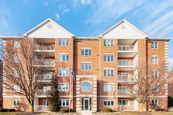 Front view of a five-story brick apartment building with balconies.