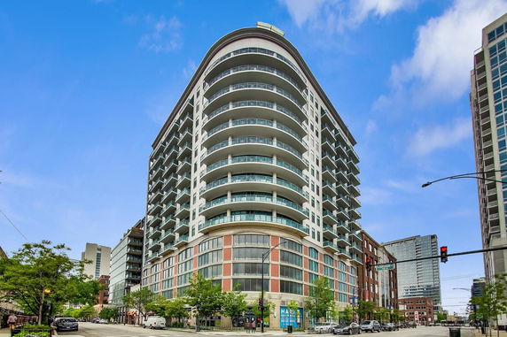 Front view of a multi-story building with rounded balconies and large windows on the lower floors.