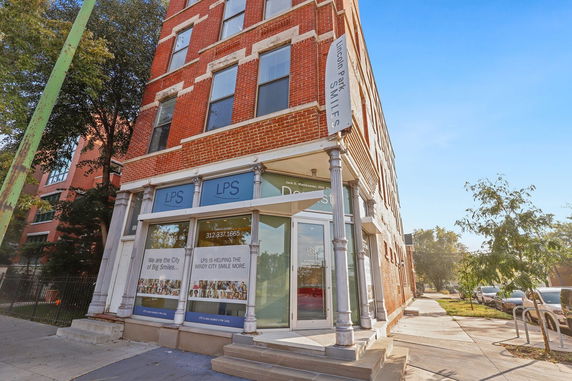 Front view of a multi-story brick building with large windows and a corner entrance.