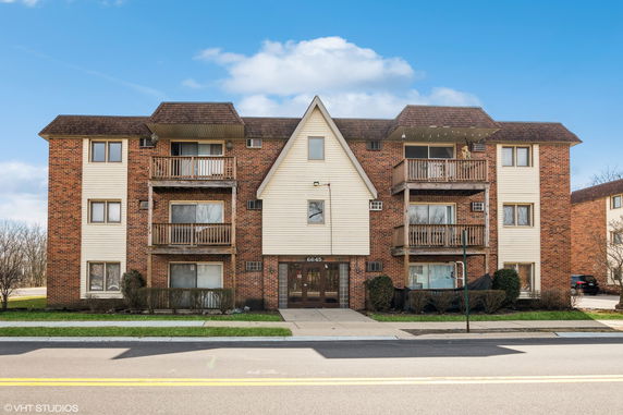 Front view of a three-story apartment building with balconies.
