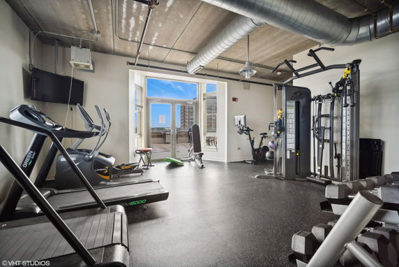 Indoor gym area with various exercise equipment and large windows.