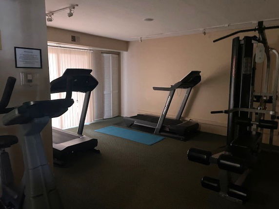 Indoor gym with exercise equipment including treadmills and a yoga mat.