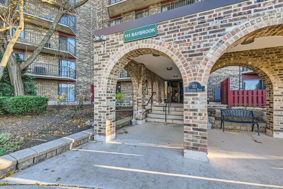 Front view of a brick building with arched entryway and multiple balconies.