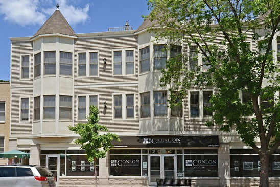 Front view of a three-story building with bay windows and commercial space on the ground floor.