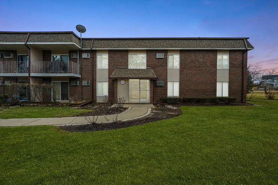 Front view of a two-story brick building with a balcony and entrance path.