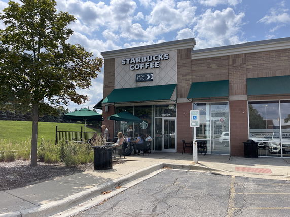 Front view of a Starbucks coffee shop with outdoor seating.