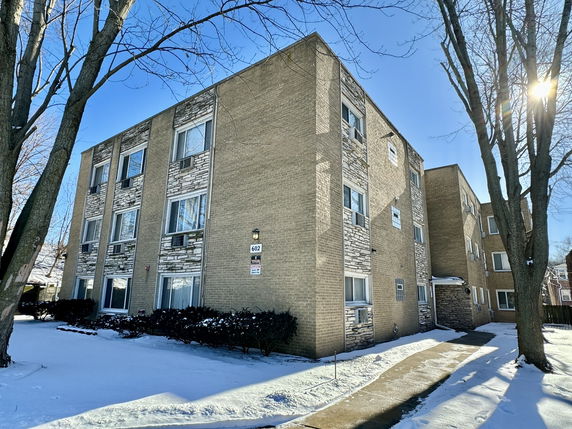 Front view of a multi-story brick apartment building with stone accents.