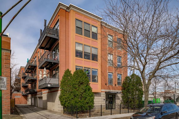 Front view of a multi-story brick apartment building with balconies.