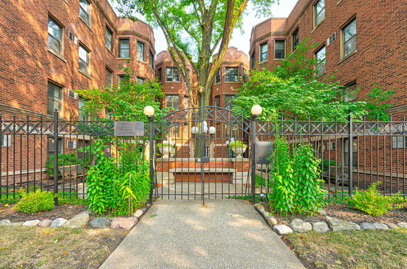 Front view of a multi-story brick building with a gated entrance.