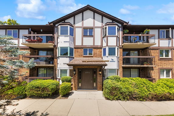 Front view of a multi-story building with balconies and brick facade.